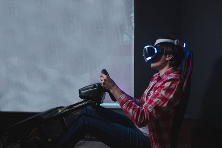 玩家在黑色背景下玩 Vr 比赛。虚拟现实的汽车模拟器。一个男人坐在汽车模拟器后面, 在 Vr 眼镜上玩游戏。