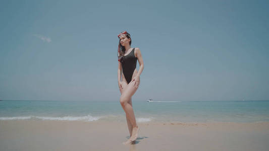 美丽的年轻女子泳装与浮潜站在沙滩上的海洋和天空背景。美丽的女孩享受阳光明媚的夏日在她的海滩热带假日
