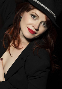 美丽的女人，在黑色的帽子和外套黑色背景