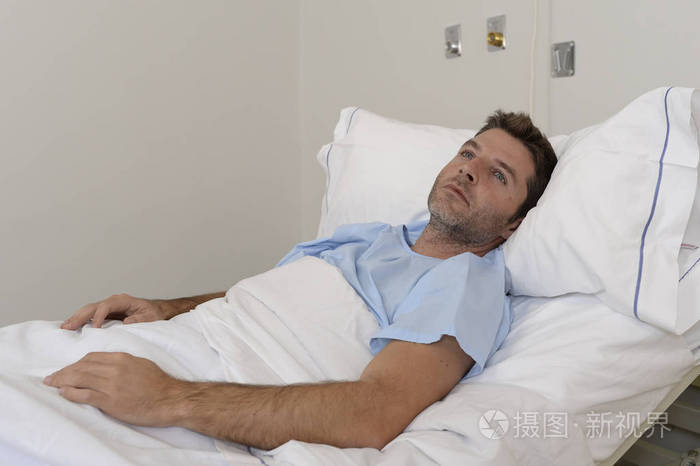 年轻有耐心的人躺在医院的床上休息累了看难过和沮丧