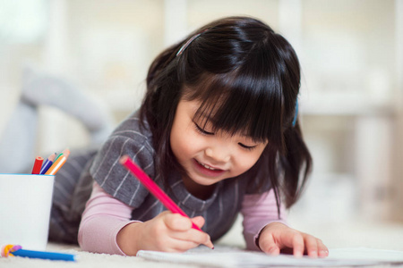 很高兴日本小女孩用铅笔在家里绘图