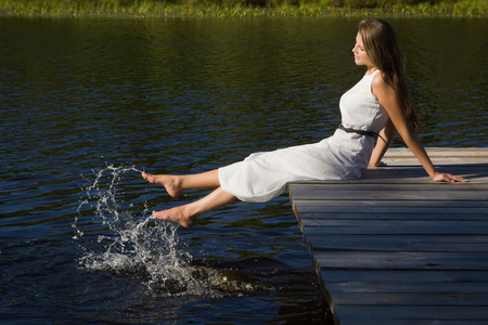 放松在木码头在湖上的年轻女子