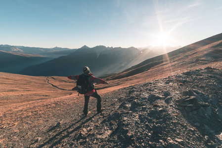 男性的徒步旅行者放松在日落时分在山区问题首脑会议和与土路穿越多彩草甸的深秋季节和迷雾笼罩的山谷下面看意大利阿尔卑斯山的雄伟壮观全