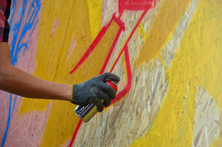 一只手用一种喷雾可以得出新的涂鸦墙上。照片的木墙特写的绘图涂鸦的过程。街头艺术和非法破坏的概念