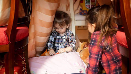 在卧室的帐篷里和姐姐玩的可爱的学步男孩肖像