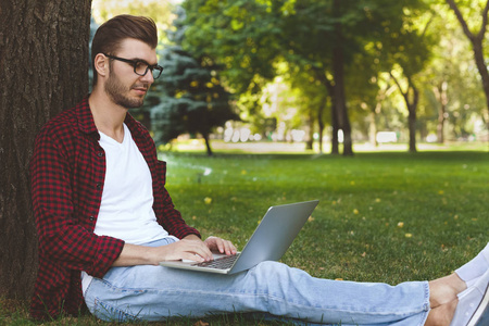 男人坐在草地上, 笔记本电脑在户外