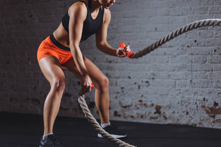 关闭运动妇女的照片在健身房做战斗绳索练习