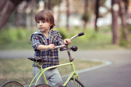 快乐的男孩，与自行车在秋天公园。