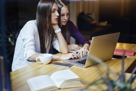 集中的时髦女孩在 coworking 空间的笔记本电脑设备的考试准备过程中浏览网上购物网站。青少年使用互联网搜索信息