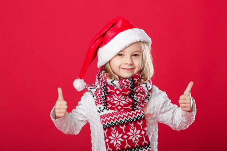 在圣诞老人的帽子和围巾红色背景上的小女孩
