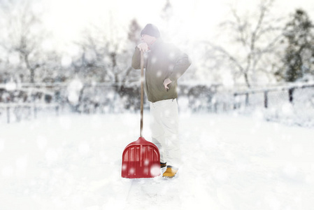 男人在降雪期间用铲子除雪上后院
