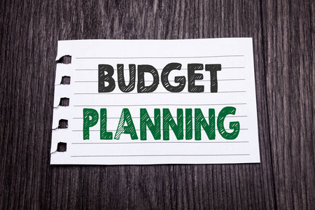 文字, 写预算计划。财务预算的商业概念写在粘纸上的暗木背景。黑色和绿色