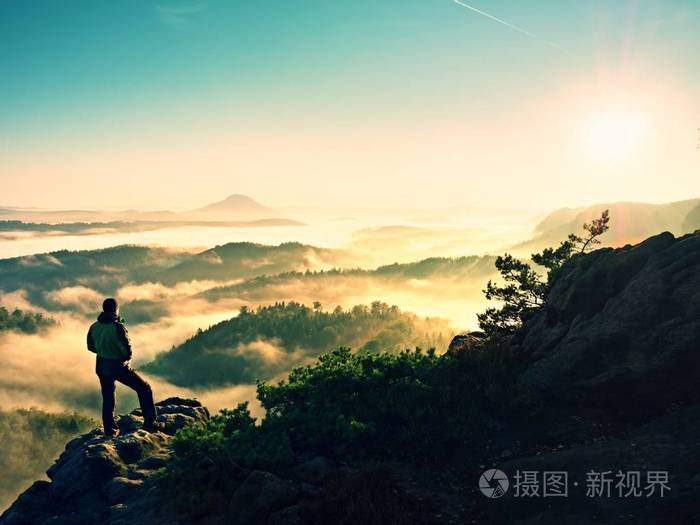 人剪影高爬上悬崖.爬到山顶的徒步旅行者欣赏的景色