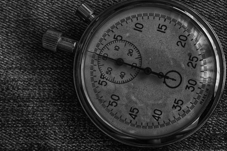 秒表在破旧的牛仔裤背景, 价值测量时间, 老时钟箭头分钟和第二精度计时器记录