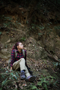女徒步旅行者在森林里休息坐在附近瀑布享受大自然