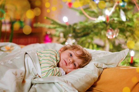 小可爱的孩子男孩睡在圣诞树下