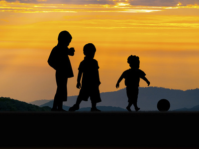 三个小男孩玩在落日的天空的轮廓