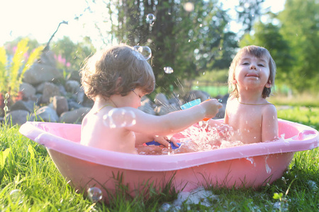 可爱的金发小美女夏季玩水溅在球场上