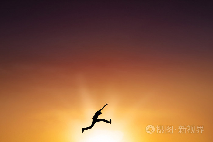 在黄昏的时候在空中飞跃的男性人