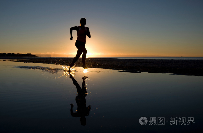 日落时分在海滩上奔跑的年轻女子