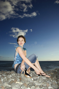 女性坐在岩石海岸。