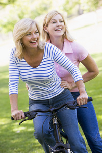 两个朋友在户外同一辆自行车上微笑