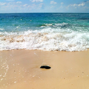 沙子里的石头和它后面的波浪。