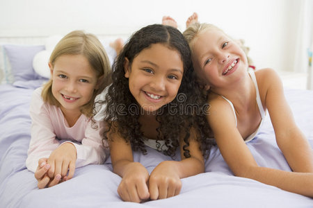 三个穿着睡衣躺在床上的年轻女孩