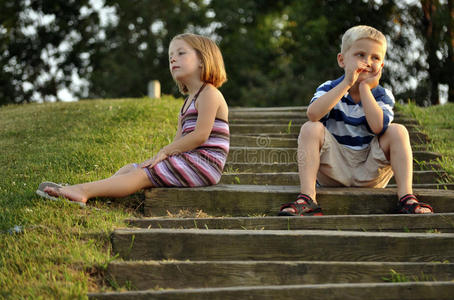 坐在公园台阶上的可爱的男孩和女孩