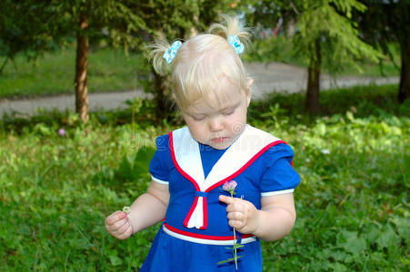 穿着水手蓝裙子的小女孩在公园里散步。