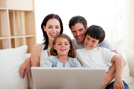 在沙发上使用笔记本电脑的微笑家庭