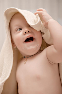面带微笑的孩子洗完澡，身上裹着柔软的毛巾