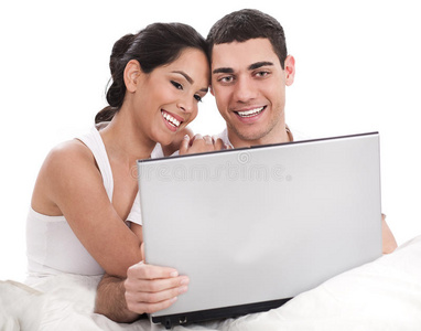 夫妻俩坐在床上拿着笔记本电脑