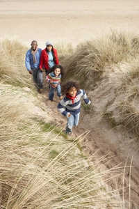 一家人在冬季海滩的沙丘上散步