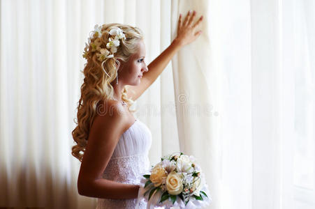 幸福的新娘带着鲜花在窗前