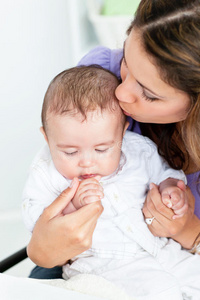 一位可爱的母亲亲吻婴儿的画像图片