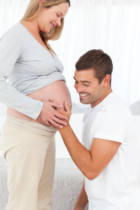 幸福的男人感受他怀孕妻子的肚子