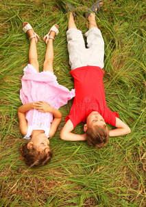 穿着粉红色连衣裙的兄妹躺在草地上