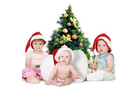 皮草树旁戴着圣诞帽的孩子们图片