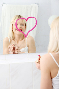 年轻漂亮的女人在镜子上画大心脏。