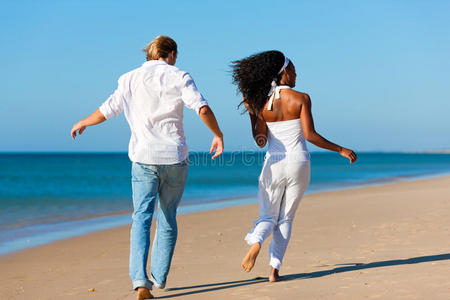 快乐夫妻在沙滩上散步和跑步