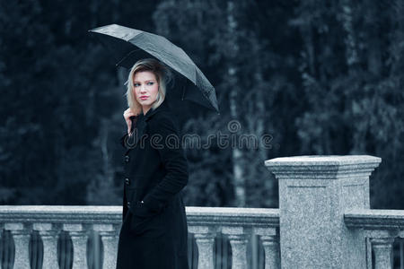悲伤的年轻时尚女士带着雨伞走在户外