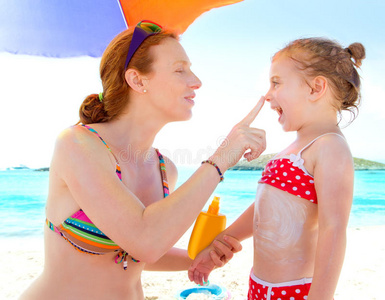 带着防晒霜在海滩上的女儿和母亲