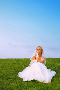 穿着白裙子的新娘坐在草地上