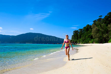 沿着海滩奔跑的年轻女子