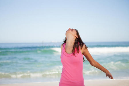 站在海滩上双臂张开的放松的年轻女子