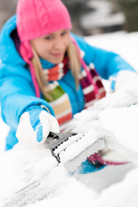 冬天擦汽车挡风玻璃上的雪的女人