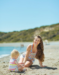 快乐的妈妈和宝宝在沙滩上玩沙子