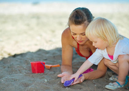 母亲和女婴在沙滩上玩沙子