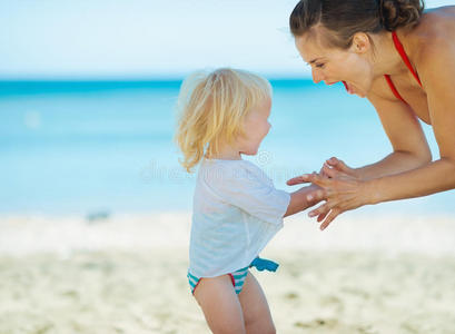快乐的妈妈和小女孩在沙滩上玩耍